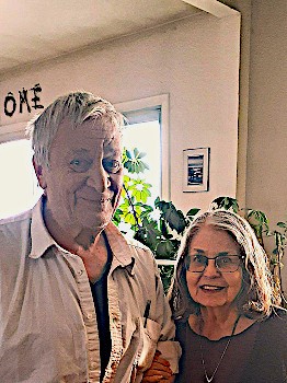 seniors standing close together while she holds his arm and they are both smiling